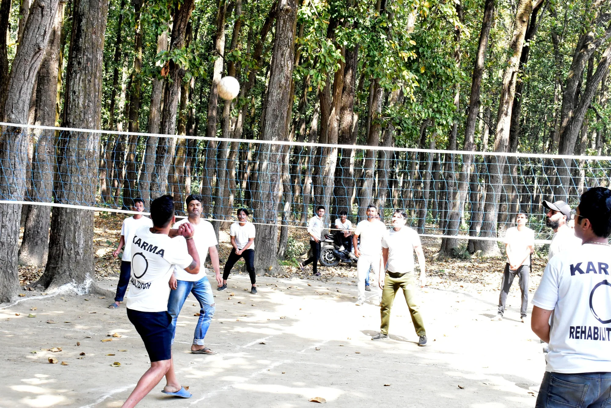 Karma team playing outdoor volleyball beneath trees